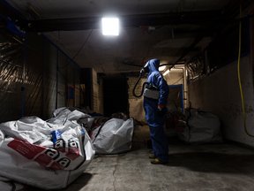 Arbeiter in Schutzanzug bei Asbestsanierung in abgedunkeltem Raum.