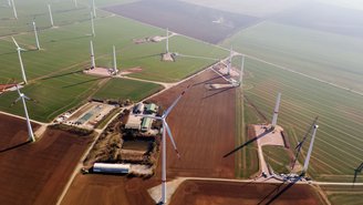 Bau von Windrädern im Windpark, umgeben von landwirtschaftlichen Flächen.