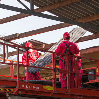 Hagedorn-Arbeiter in Schutzanzügen auf Hebebühne bei Sanierungsarbeiten.
