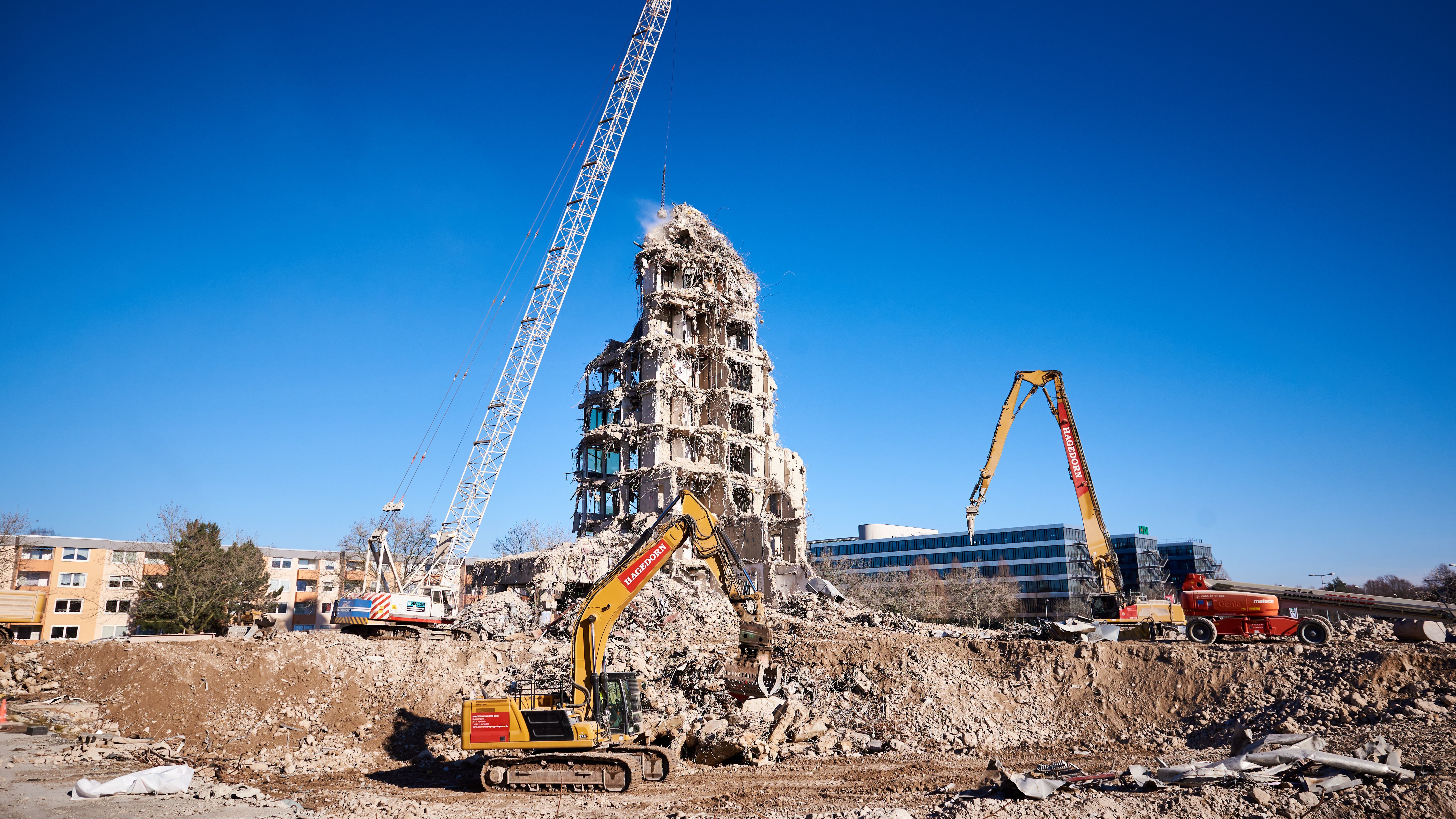 Bagger demontiert Gebäudestrukturen auf Baustelle.