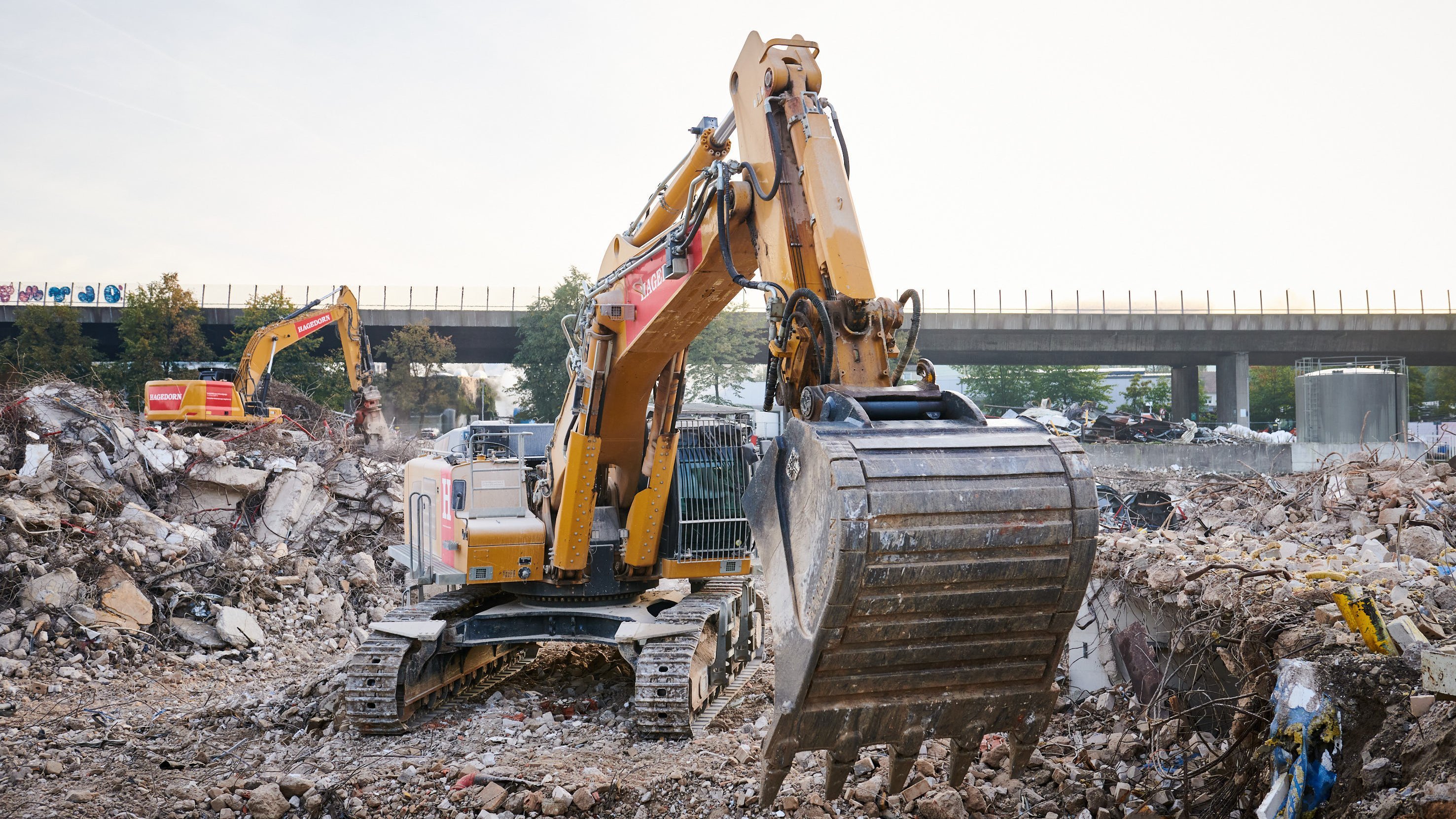 Gelbe Bagger bei der Arbeit an einer Baustelle mit viel Schutt.