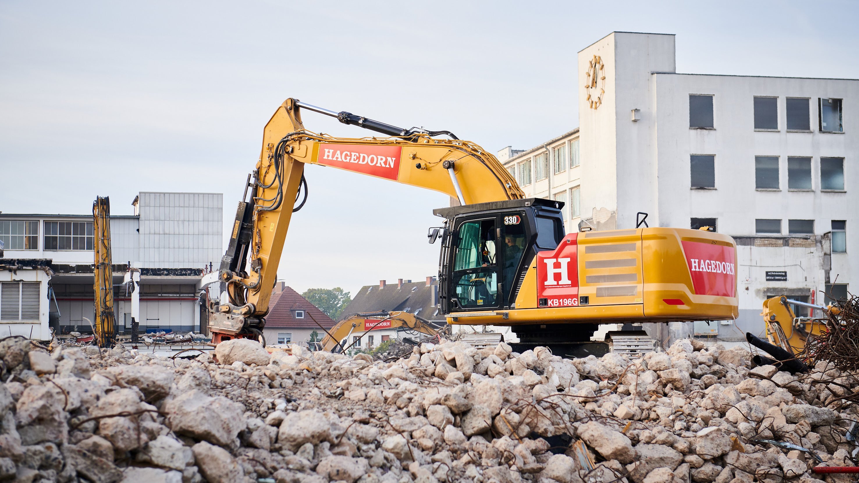 Baumaschine auf Abbruchstelle umgeben von Schutt und Gebäuderesten.