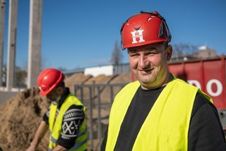 Arbeiter mit Helm lächelt auf Baustelle.