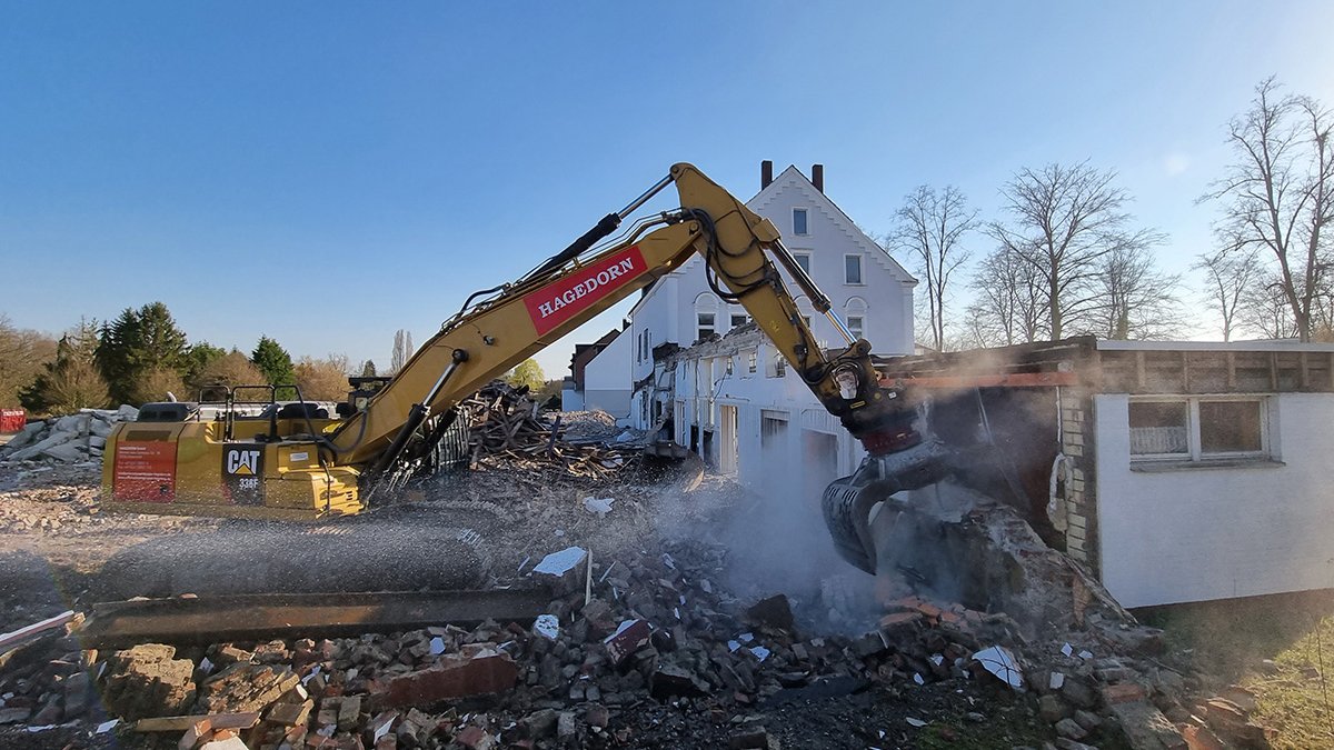  Excavator dismantles house wall under a clear sky