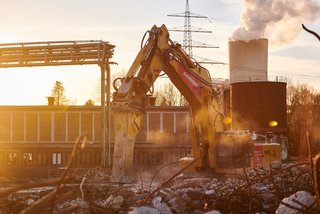 Bagger im Abbrucheinsatz bei Sonnenuntergang, Industriekulisse.