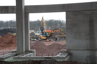 Blick durch Betonrahmen auf Hagedorn-Bagger im Einsatz.