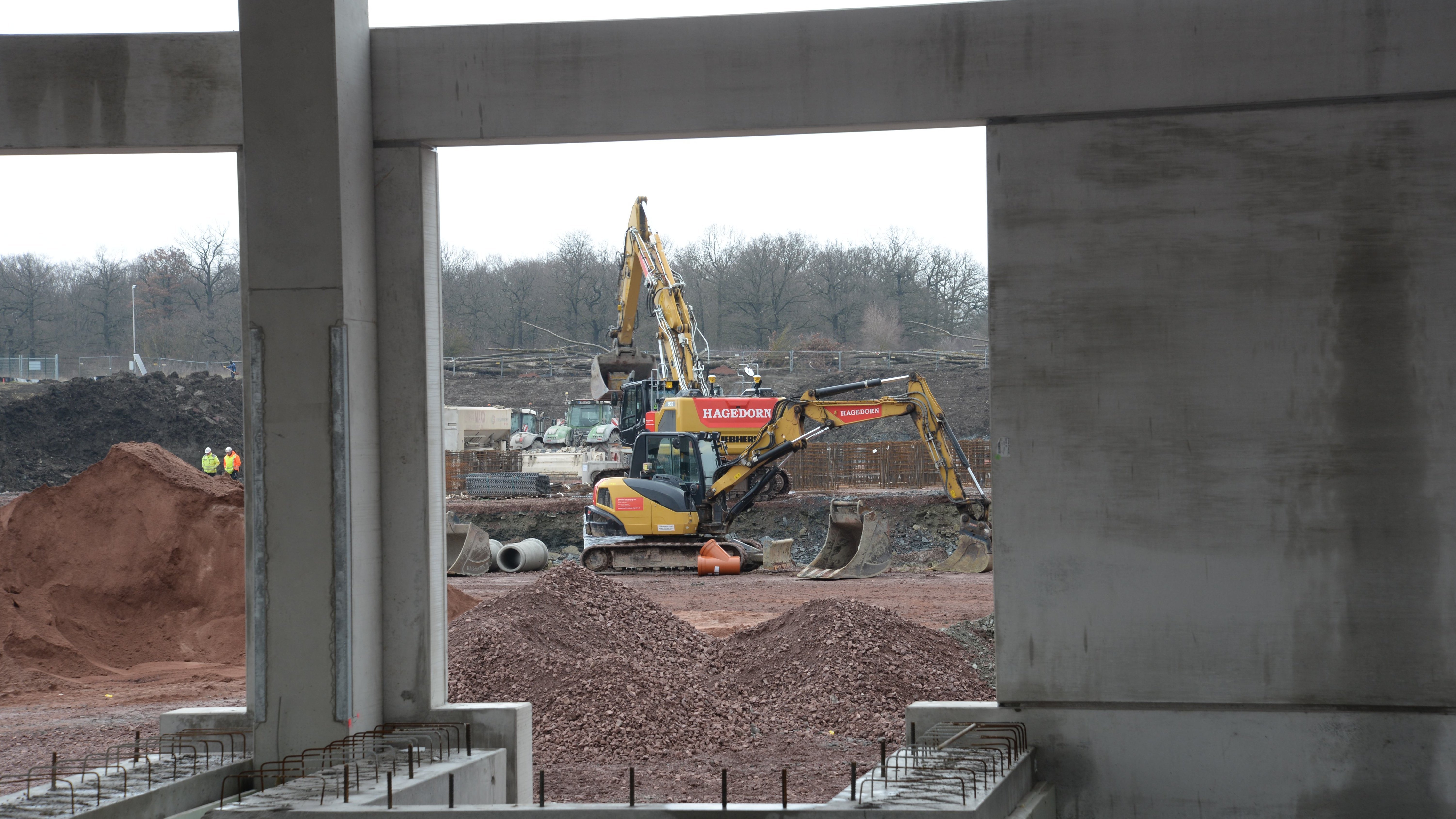 Blick durch Betonrahmen auf Baggerarbeiten im Hintergrund.