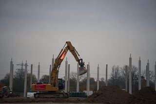 Bagger hebt Material auf Baustelle.
