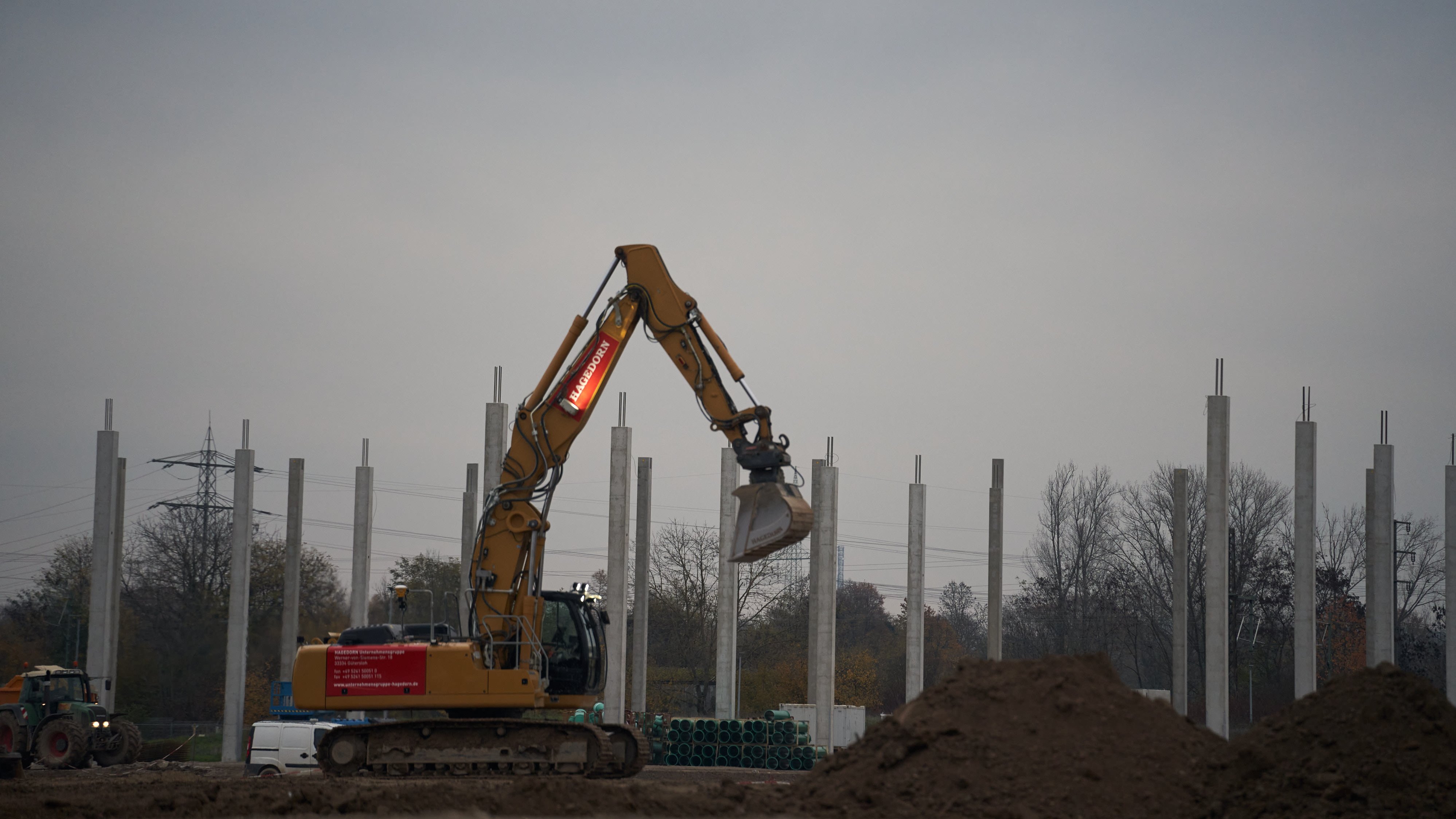 Bagger arbeitet zwischen Betonpfeilern.