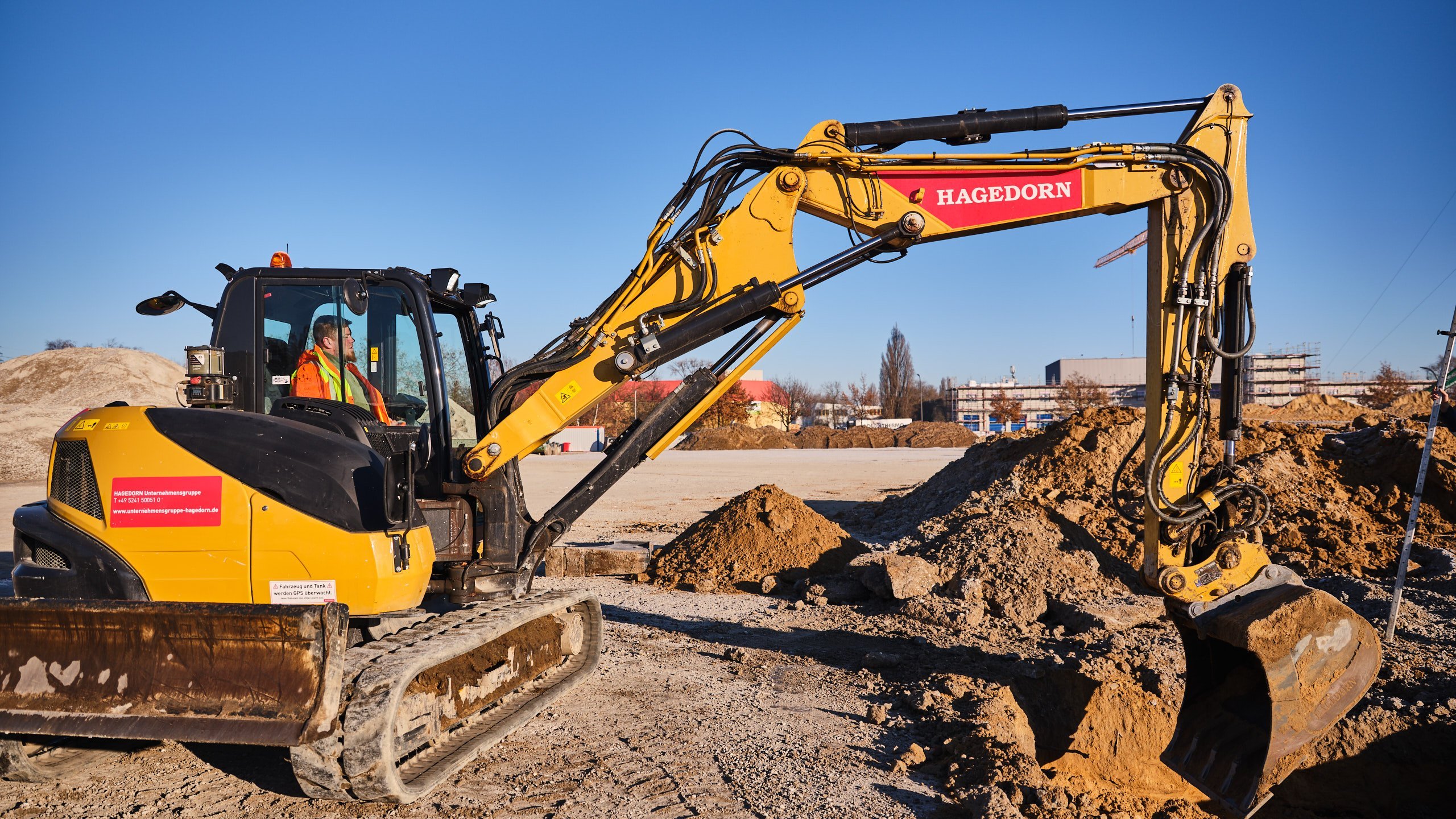 Gelber Bagger bereitet Gelände auf Baustelle vor.