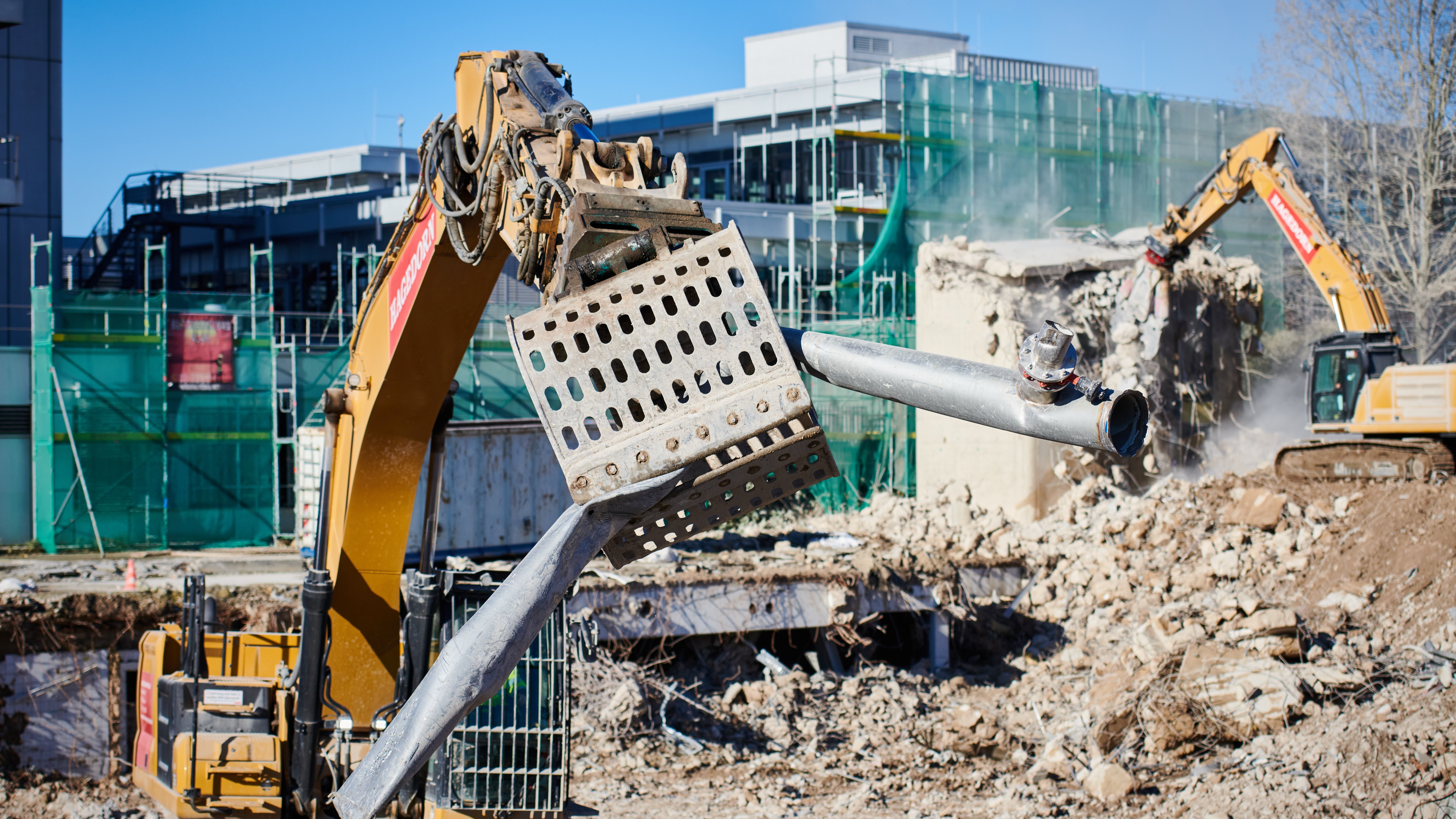 Bagger bei Abrissarbeiten mit Staubwolke.