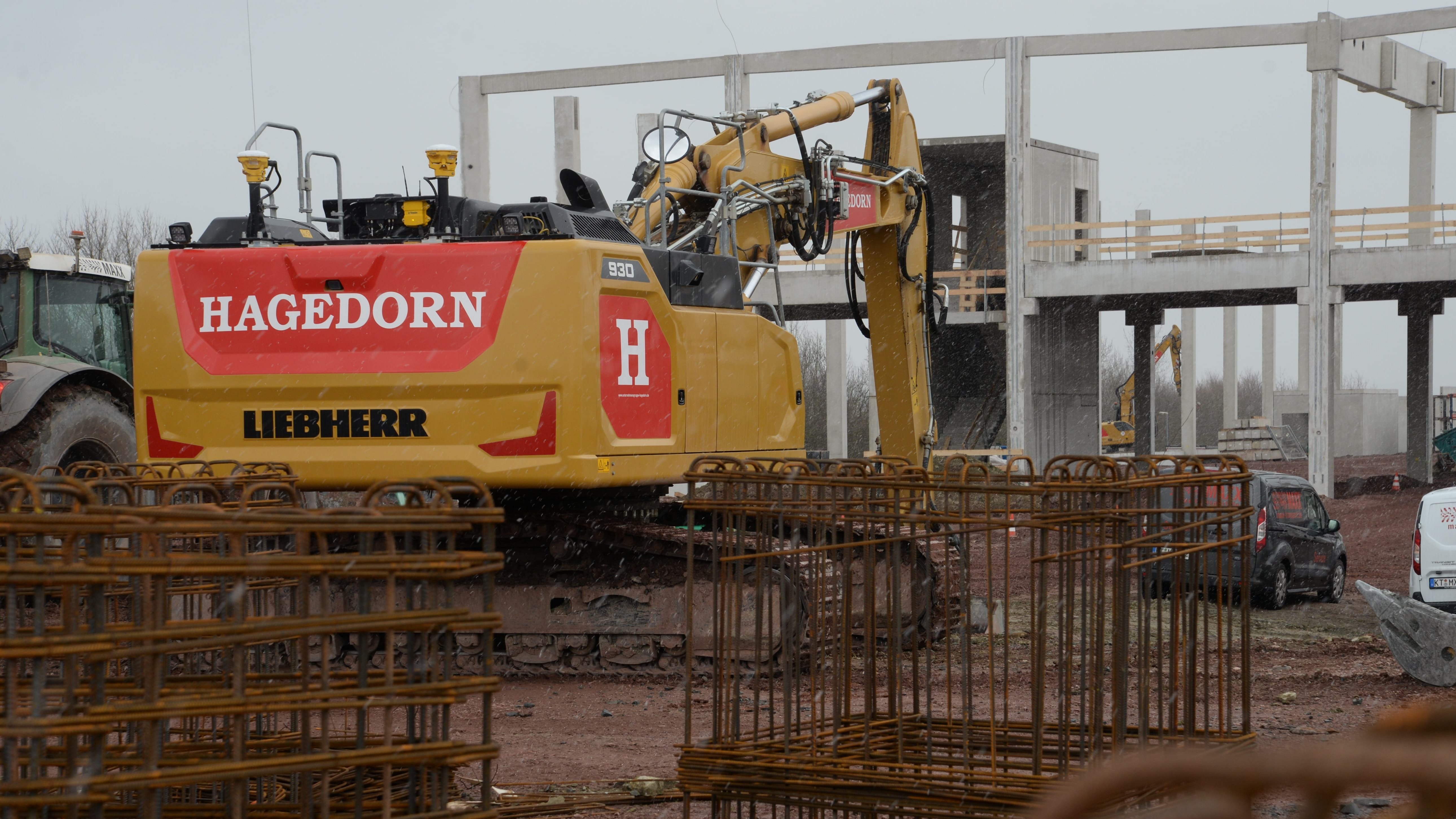 Bauarbeiten mit Bagger neben Betonkonstruktionen.