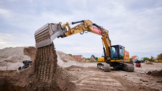 Tiefbau in Aktion: Bagger schaufelt Erde auf Baufeld.