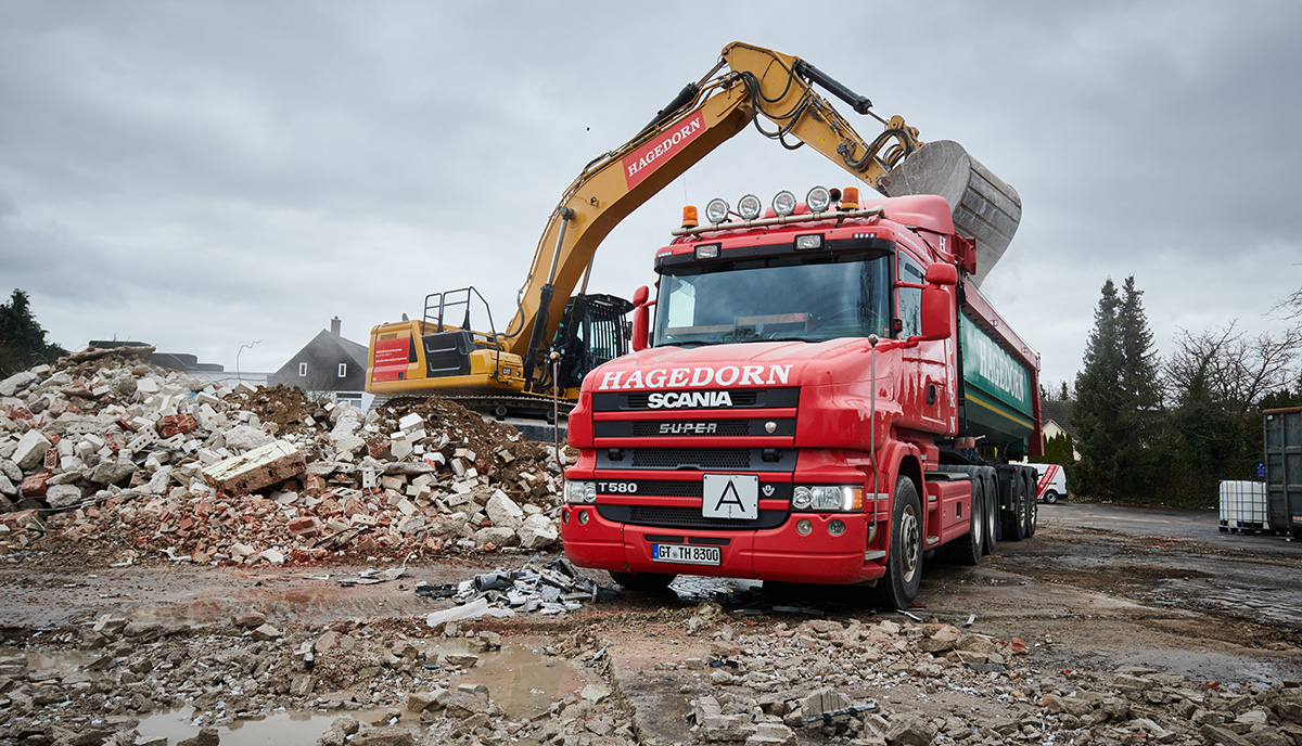 LKW und Bagger bei der Beladung von Trümmern auf einer Baustelle